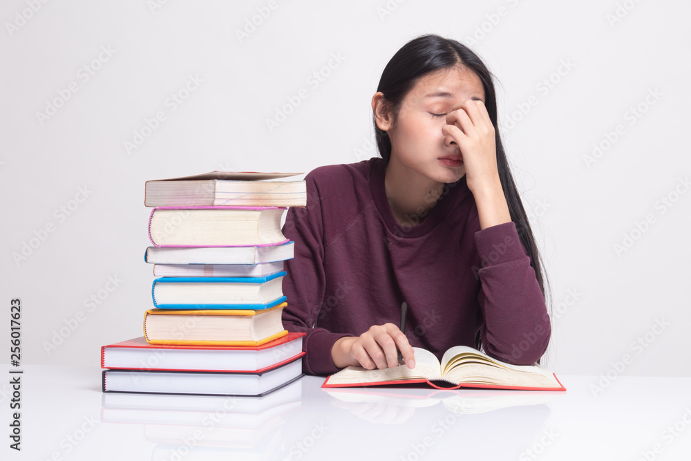 Exhausted Asian woman got headache read a book with books on table. Exhausted Asian woman got headache read a book with books on table.