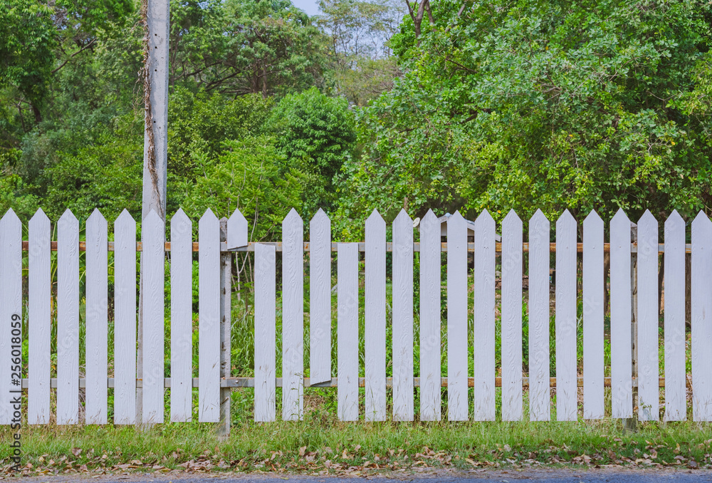 Old white wooden fence with a broken board at the roadside area