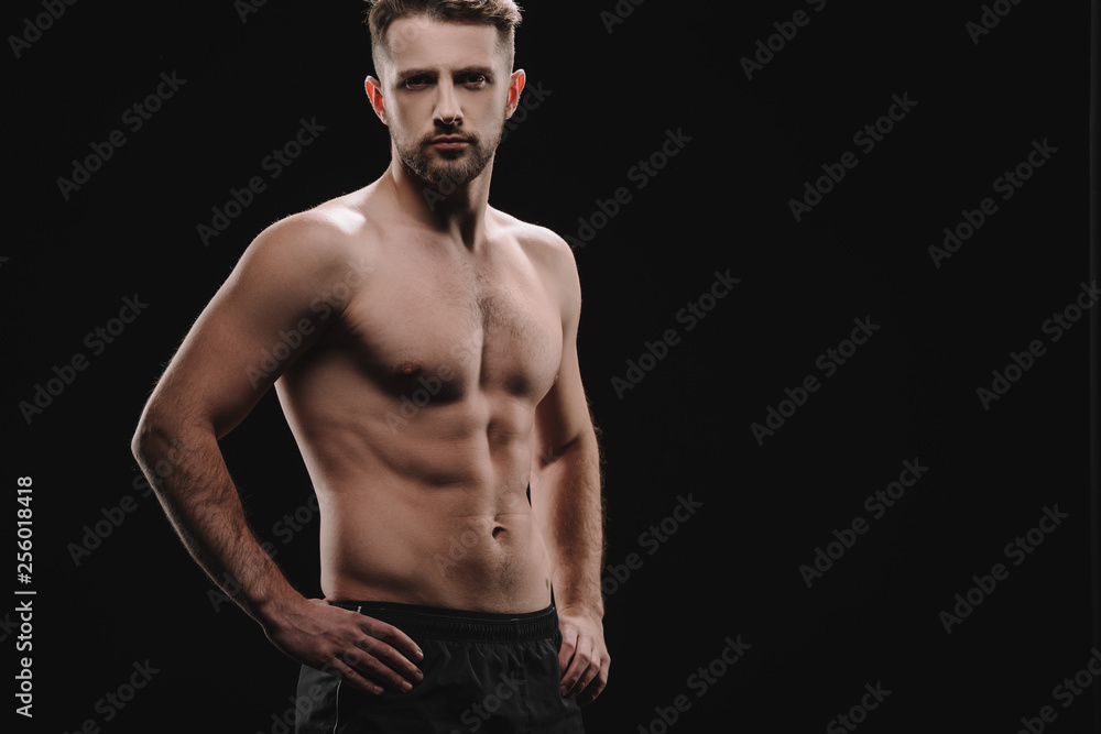 Fototapeta premium strong athletic muscular sportsman with hands on hips looking at camera isolated on black