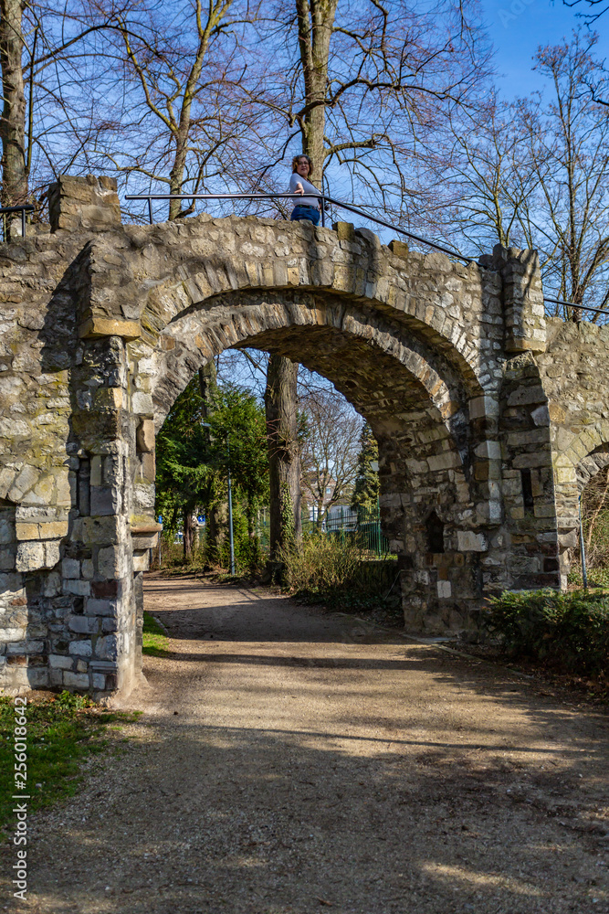 Dirt road and the arch of an old stone bridge with a woman on it, a dirt road in the Proosdij park, a wonderful and sunny day in Meerssen south Limburg in the Netherlands Holland