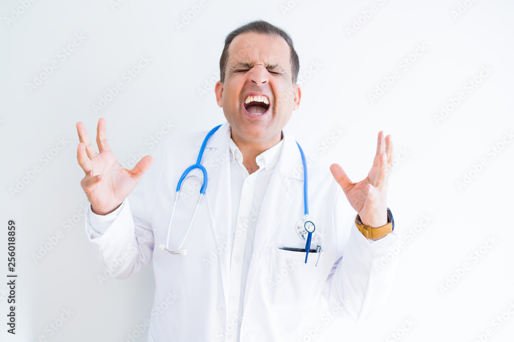 Middle age doctor man wearing stethoscope and medical coat over white background celebrating mad and crazy for success with arms raised and closed eyes screaming excited. Winner concept Middle age doctor man wearing stethoscope and medical coat over white background celebrating mad and crazy for success with arms raised and closed eyes screaming excited. Winner concept