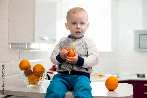 Cute toddler with fruits in kitchen.