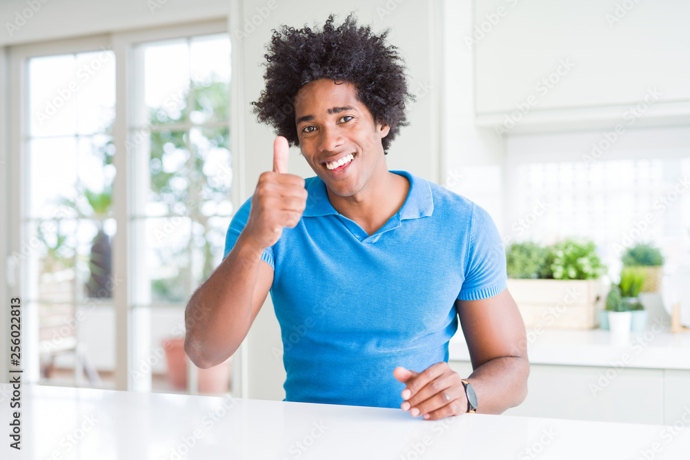 African American man at home doing happy thumbs up gesture with hand. Approving expression looking at the camera with showing success. African American man at home doing happy thumbs up gesture with hand. Approving expression looking at the camera with showing success.