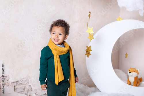 Close-up portrait of a black boy's face, afro-american. The little black boy is smiling. Cute baby, baby in the game. Pretty smile. Curly hair. Mulat. Adventures of the little prince in the month. photo