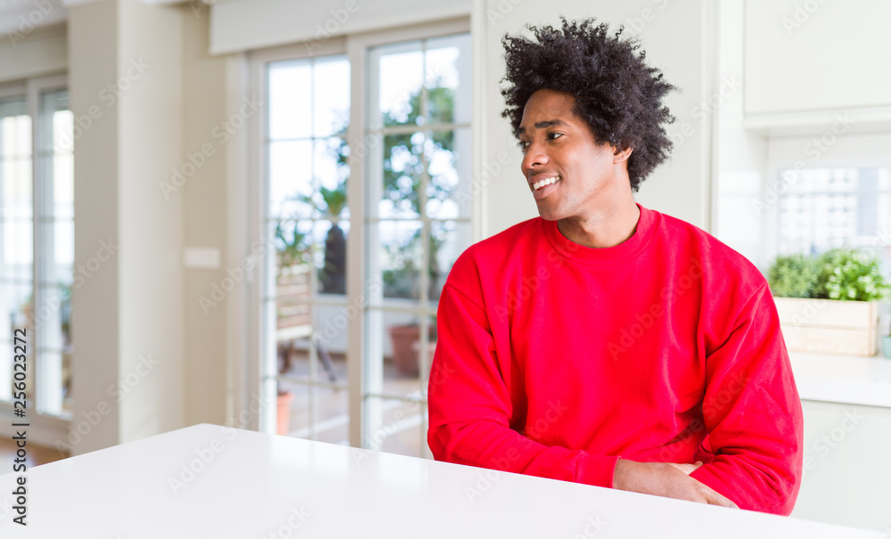 African American man wearing casual red sweatshirt looking away to side with smile on face, natural expression. Laughing confident. African American man wearing casual red sweatshirt looking away to side with smile on face, natural expression. Laughing confident.