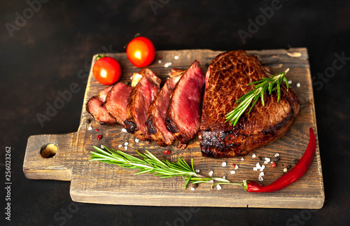 Beef steak, herbs and spices on a cutting board against a background of stone