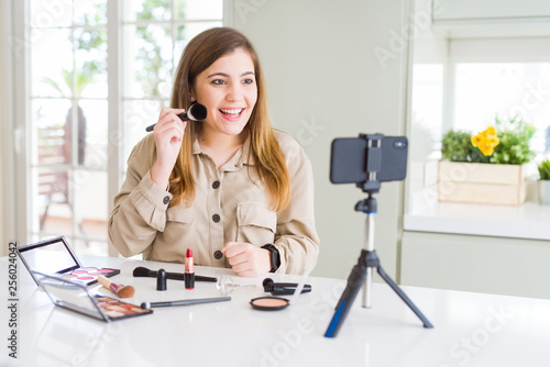 Beautiful young influencer woman recording make up video tutorial with a happy face standing and smiling with a confident smile showing teeth