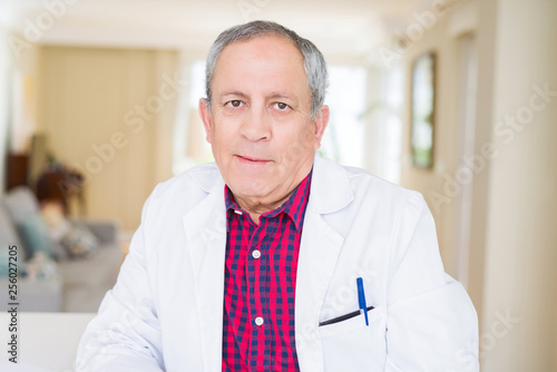 Senior doctor man wearing medical coat at the clinic and smiling