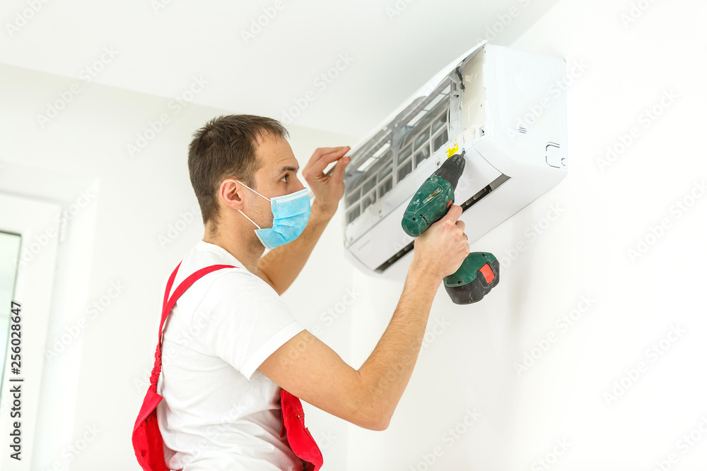 Male technician cleaning air conditioner indoors Male technician cleaning air conditioner indoors