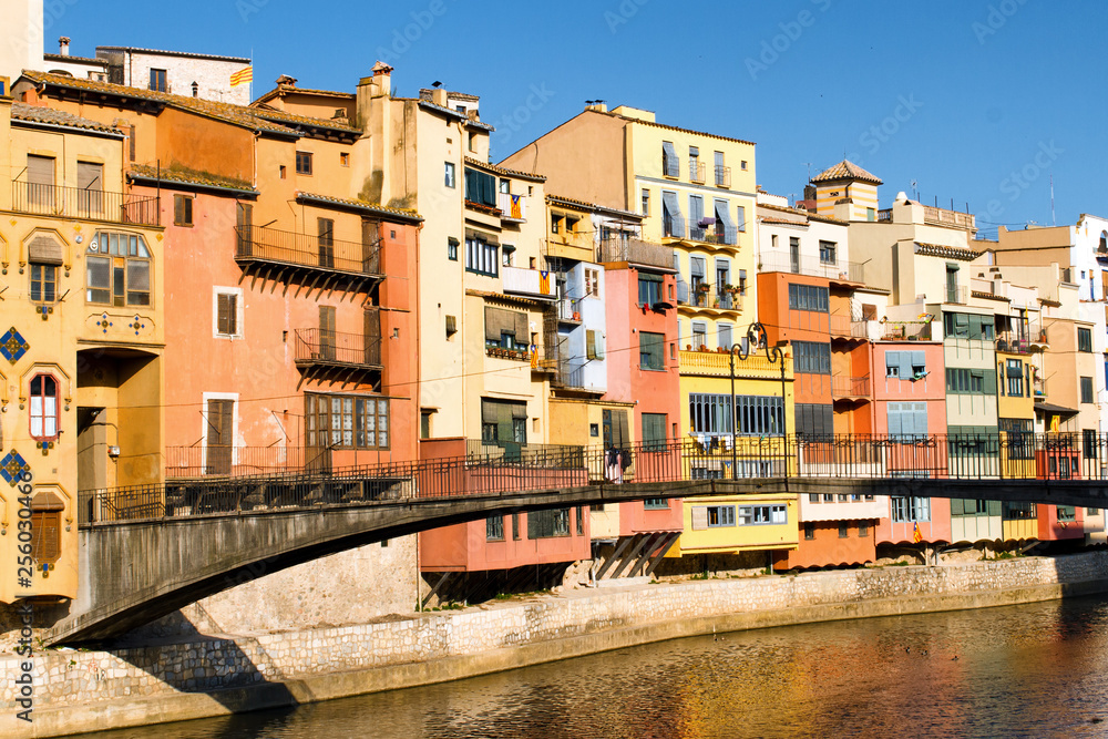 Colorful houses and Gomez bridge against blue sky in Girona, Catalonia, Spain. Selective focus on buildings