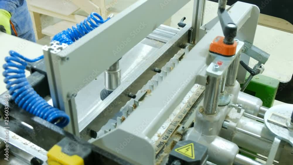 A carpenter works behind a drilling machine, adding furniture parts to a furniture factory. A carpenter works behind a drilling machine, adding furniture parts to a furniture factory.