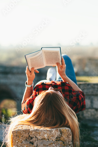 Young woman enjoying reading a book in public park
