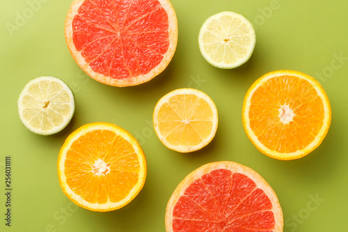 Colorful sliced fruits background. Grapefruit, lime, lemon and orange on green background