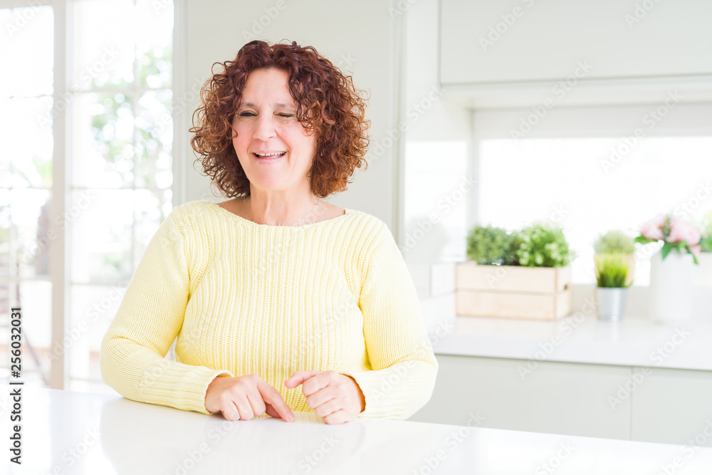 Beautiful senior woman wearing yellow sweater winking looking at the camera with sexy expression, cheerful and happy face. Beautiful senior woman wearing yellow sweater winking looking at the camera with sexy expression, cheerful and happy face.