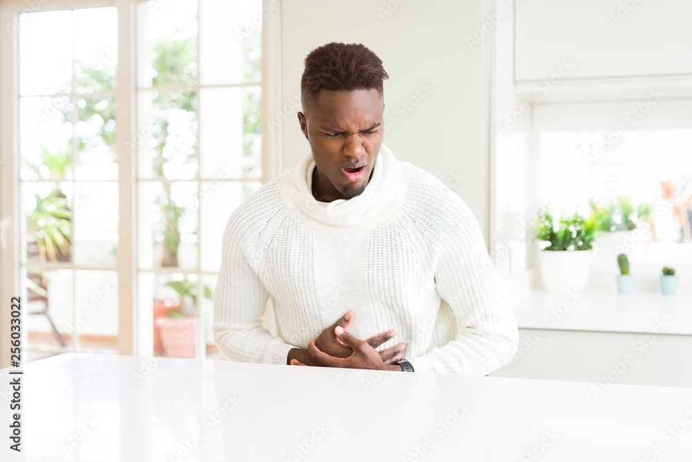 Handsome african american man on white table with hand on stomach because indigestion, painful illness feeling unwell. Ache concept. Handsome african american man on white table with hand on stomach because indigestion, painful illness feeling unwell. Ache concept.