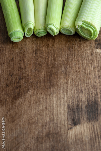 Vertical top view of leeks on dark wood background with copy space