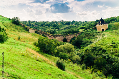 Summer view of green hills and old watchtower ruins. Khotyn Fortress location. Dramatic scene of green hills landscape. Traveling concept background