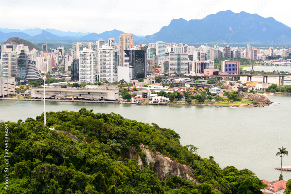 Fototapeta premium Aerial view of the beautiful city of Vitoria, Espirito Santo, Brazil and its wide bay. The city developed with its high buildings growing on the hills and into the local greenery