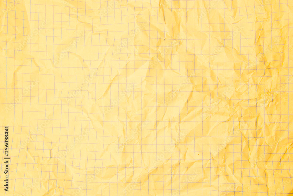 One crumpled yellow blank paper sheet of a notebook in grid (background) One crumpled yellow blank paper sheet of a notebook in grid (background)