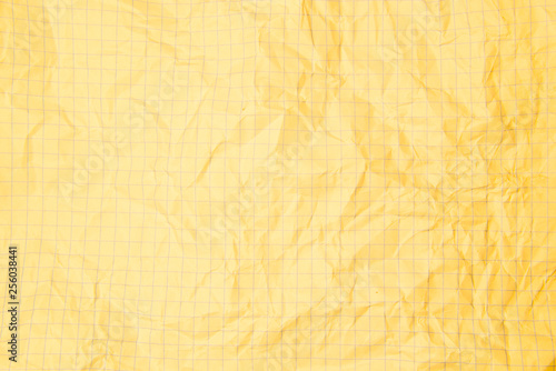 One crumpled yellow blank paper sheet of a notebook in grid (background)