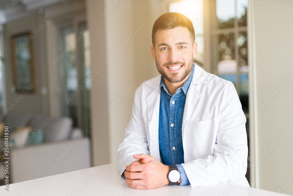 Young handsome doctor man at the clinic with a happy and cool smile on face. Lucky person. Young handsome doctor man at the clinic with a happy and cool smile on face. Lucky person.