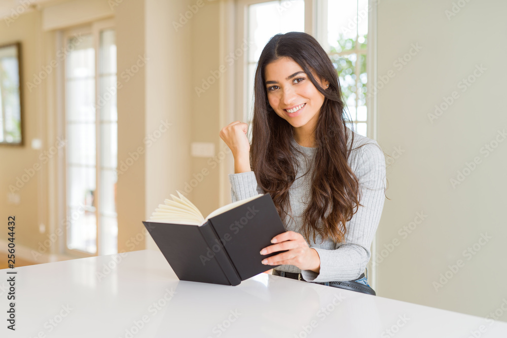 Young woman reading a book screaming proud and celebrating victory and success very excited, cheering emotion Young woman reading a book screaming proud and celebrating victory and success very excited, cheering emotion
