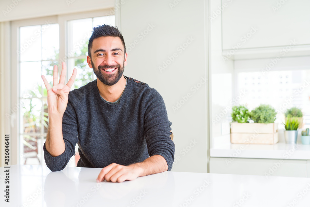 Handsome hispanic man wearing casual sweater at home showing and pointing up with fingers number four while smiling confident and happy. Handsome hispanic man wearing casual sweater at home showing and pointing up with fingers number four while smiling confident and happy.