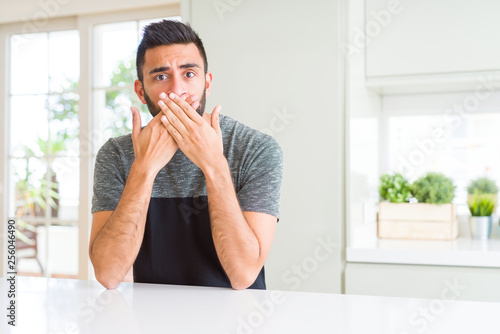 Handsome hispanic man wearing casual t-shirt at home shocked covering mouth with hands for mistake. Secret concept.