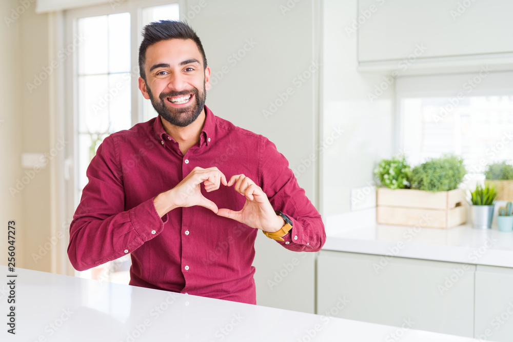 Handsome hispanic business man smiling in love showing heart symbol and shape with hands. Romantic concept.
