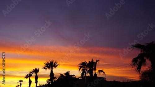 Dramatic sunset landscape at Urla, Izmir, Turkey. Beautiful blazing sunset landscape over bright blue sea and orange cloudy sky above it with awesome golden rays of sun light reflection on calm waves.