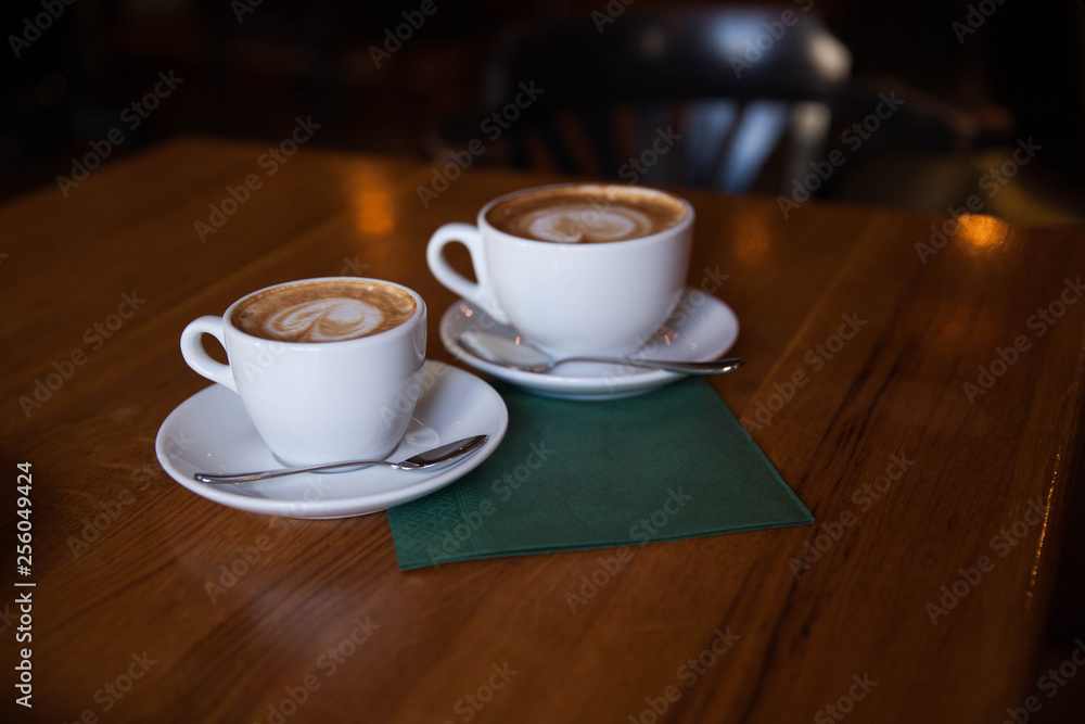 Two cups of cappuccino on a wooden table Two cups of cappuccino on a wooden table