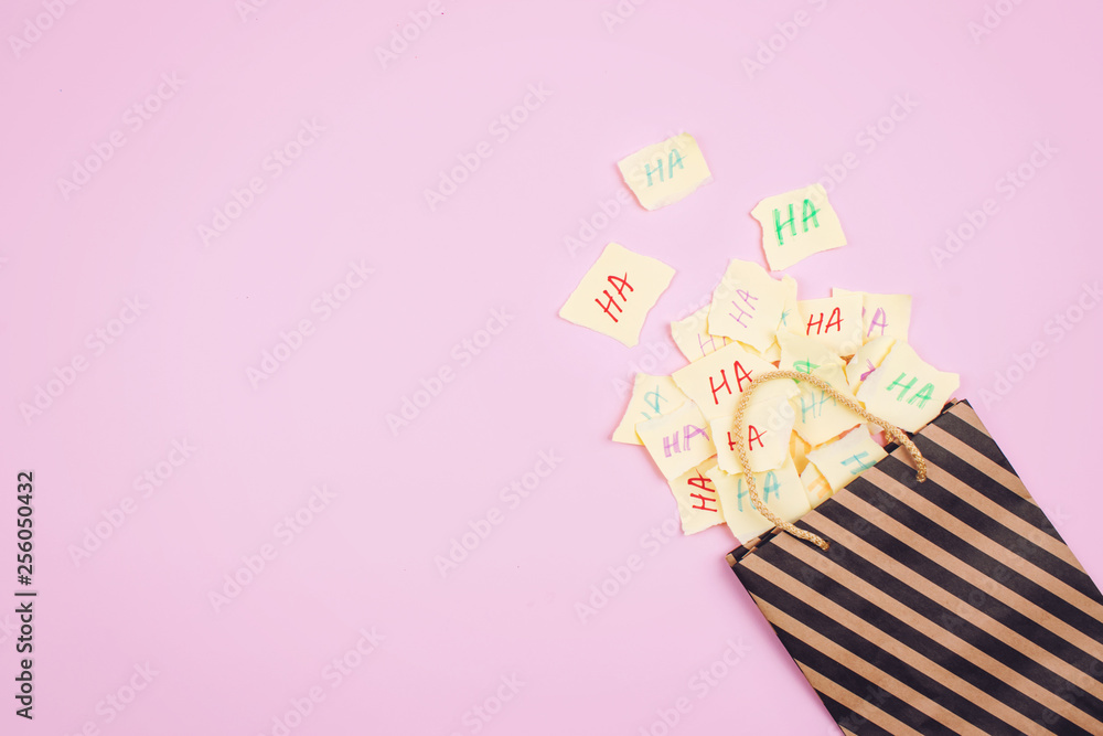 April Fools' Day celebration background. Paper bag with many paper sheets  with the words haha. 1 April mockup on pink background. All Fools' Day,  humor, prank, joke concept. Photos | Adobe Stock