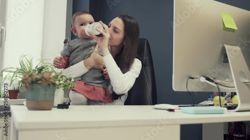 Working mother with toddler at baby friendly office, working sucsessful female entrepreneur modern motherhood photo