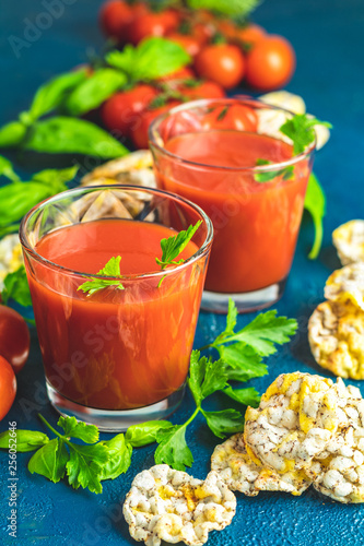 Red cocktail with tomato juice between tomatoes, basil, parsley and nutritious cereal breads