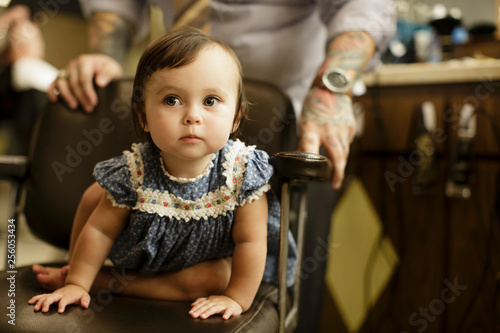 Toddler sits in barbershop chair