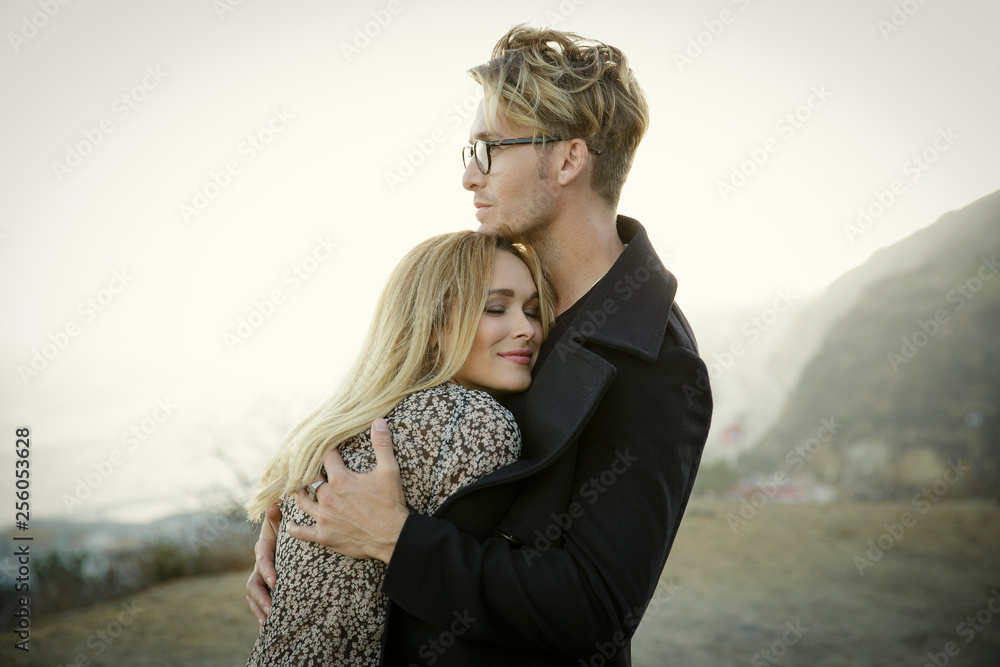 © Natalie Faye - Stylish blond couple hugs on beach