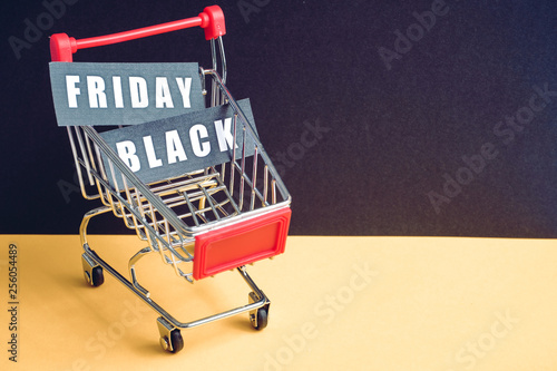 A trolley on a black background with labels containing the inscription "Black Friday". Toned. Copy space.