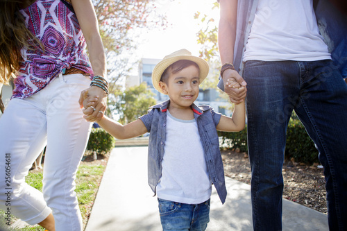 Parents hold young boy's hands