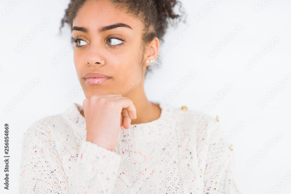 Beautiful young african american woman with afro hair wearing casual sweater with hand on chin thinking about question, pensive expression. Smiling with thoughtful face. Doubt concept. Beautiful young african american woman with afro hair wearing casual sweater with hand on chin thinking about question, pensive expression. Smiling with thoughtful face. Doubt concept.