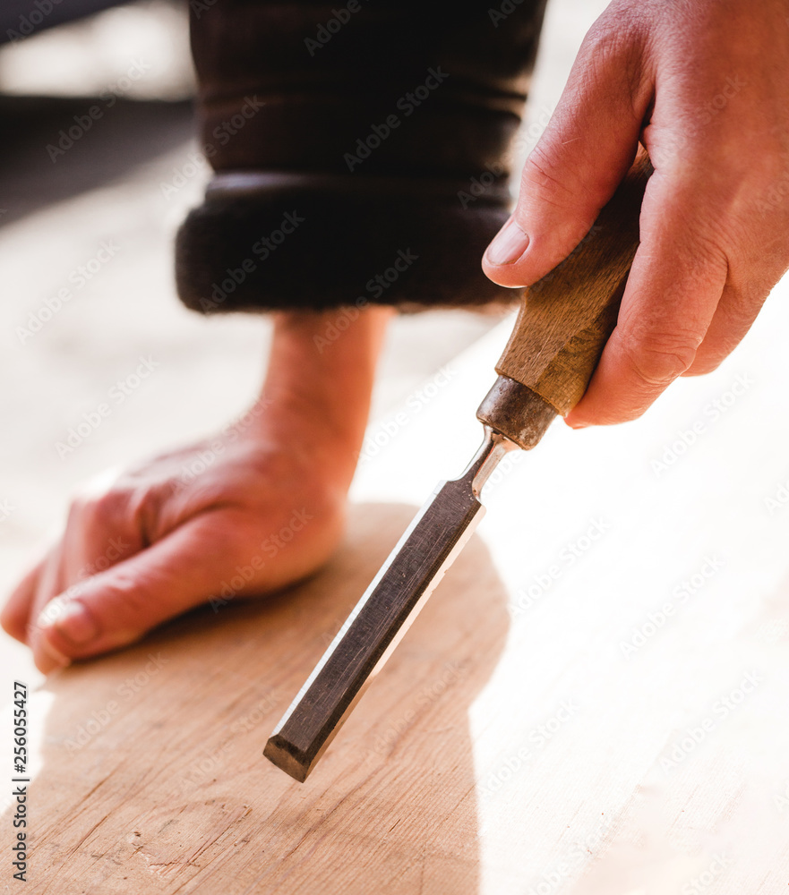 carpenter with chisel in the hands on the workbench in carpentry, close up carpenter's hands that work with cutter carpenter with chisel in the hands on the workbench in carpentry, close up carpenter's hands that work with cutter