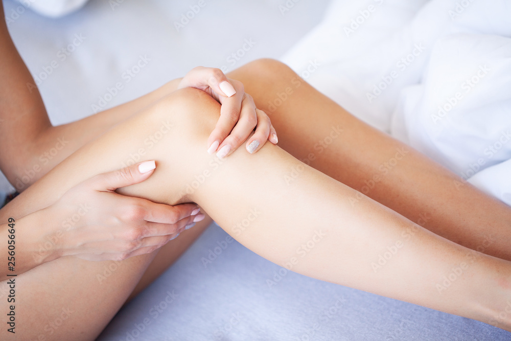 Woman legs raised up on the baggage, Young woman at home laying in bed. The white bedroom.