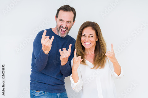Beautiful middle age couple in love over isolated background shouting with crazy expression doing rock symbol with hands up. Music star. Heavy concept.