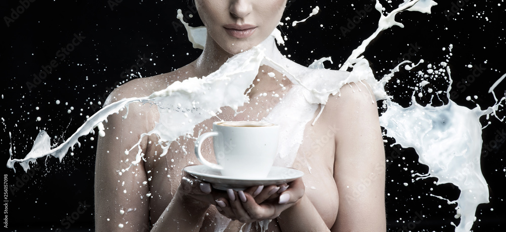 Milk splashing against a nude woman holding a cup of coffee Stock