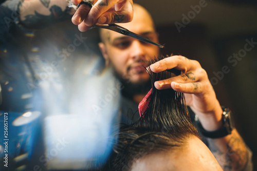 Confident bearded man visiting hairstylist in barber shop.