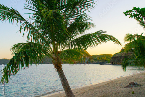 View of exotic white sand beach, sun loungers, palm trees and turquoise water at Fiji Islands. Calm, relaxing, inspiring mood. Travel / summer holidays / vacation concept. Beautiful holiday background