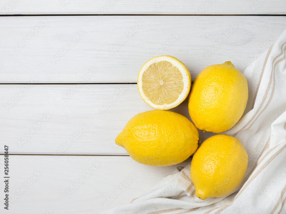 Whole and sliced lemons with fabric on white wooden background. Organic fresh citrus fruits, top view, copy space. Whole and sliced lemons with fabric on white wooden background. Organic fresh citrus fruits, top view, copy space.