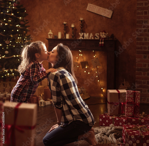 Conceptual portrait of a mother kissing a daughter, christmas items in background