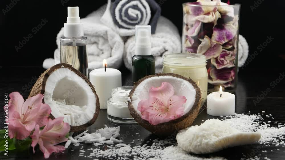 Accessories for spa treatments and aromatherapy with coconut. Burning candle, coconut halves, flakes of coconut and coconut based cosmetics on a black background Accessories for spa treatments and aromatherapy with coconut. Burning candle, coconut halves, flakes of coconut and coconut based cosmetics on a black background