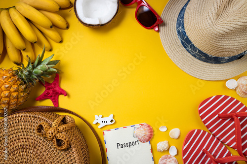 Summer female fashion beach accessories flip flop, straw hat, bamboo bag, sunglasses and tropical fruits on yellow background. Journey, vocations, travel and summer rest concept
