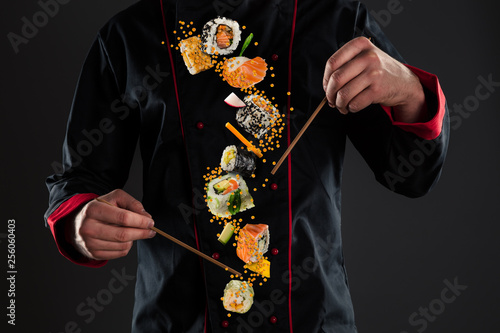 Master chef holding chopsticks with flying sushi